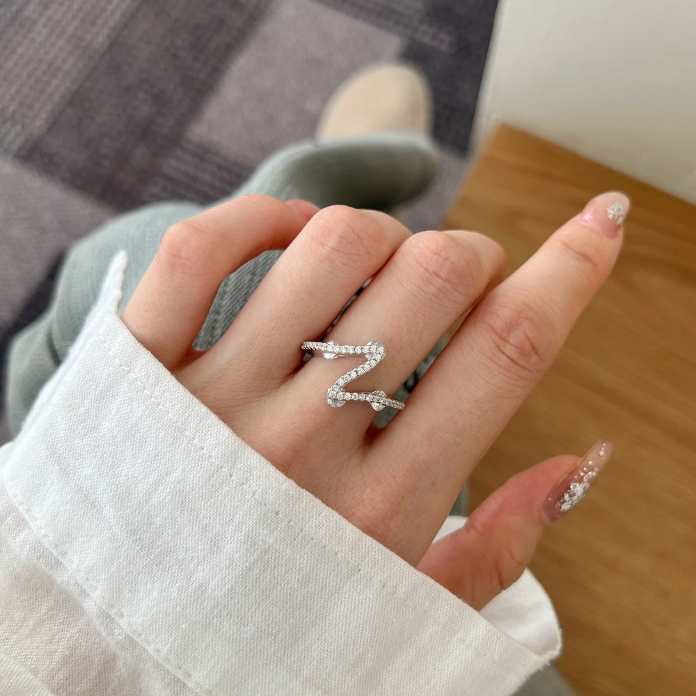 Hand wearing a silver ring with a blurred background