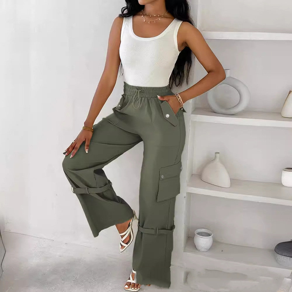 Woman wearing a white tank top and green cargo pants in a minimalistic room.