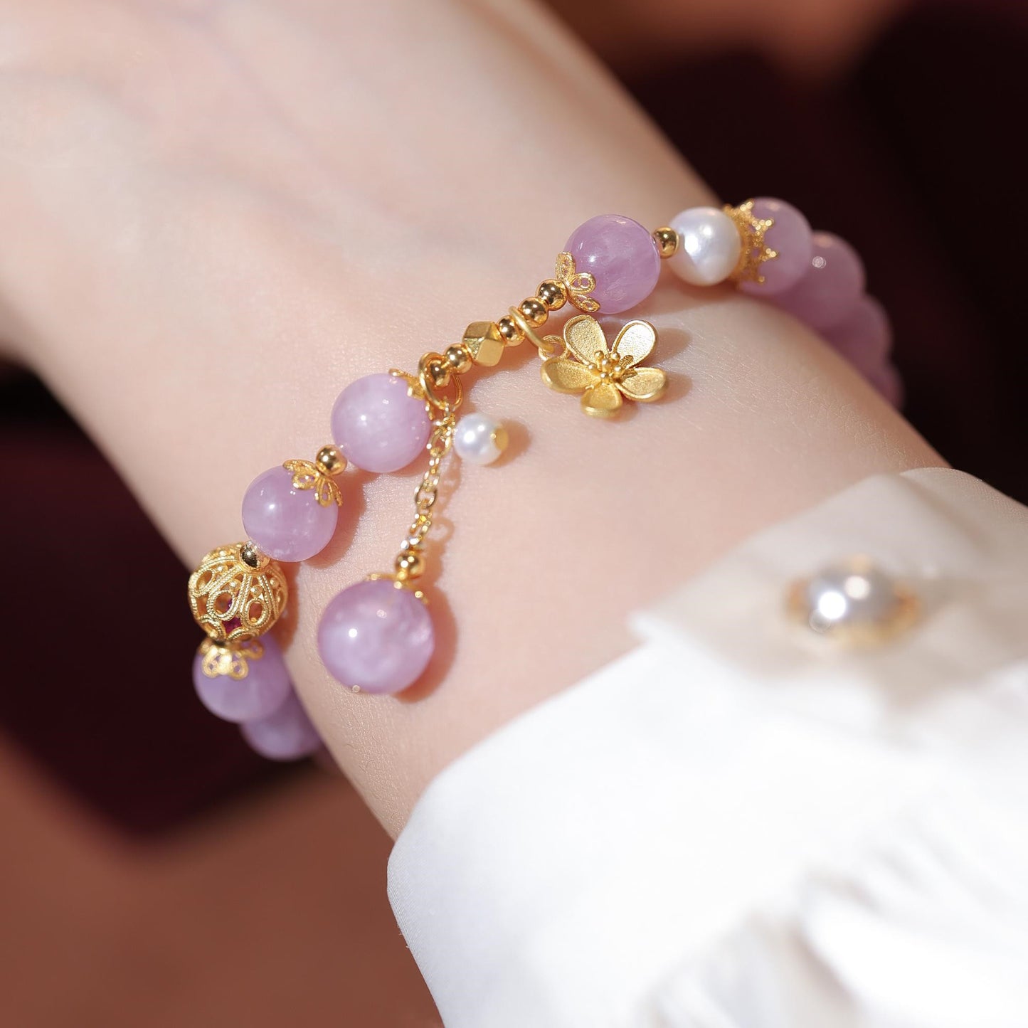 Bracelet with pink beads and gold accents on a wrist against a neutral background