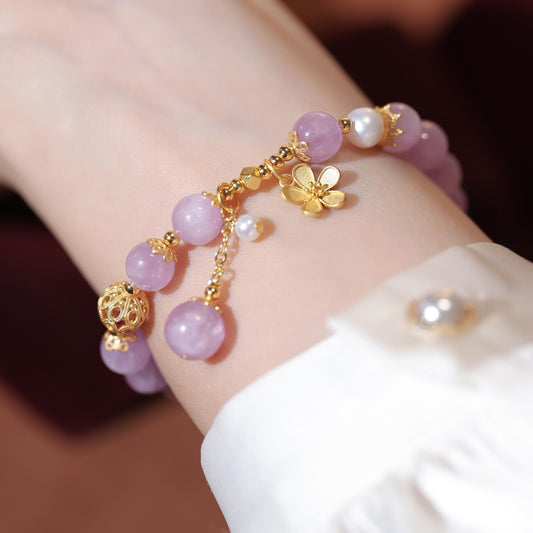 Bracelet with pink beads and gold accents on a wrist against a neutral background