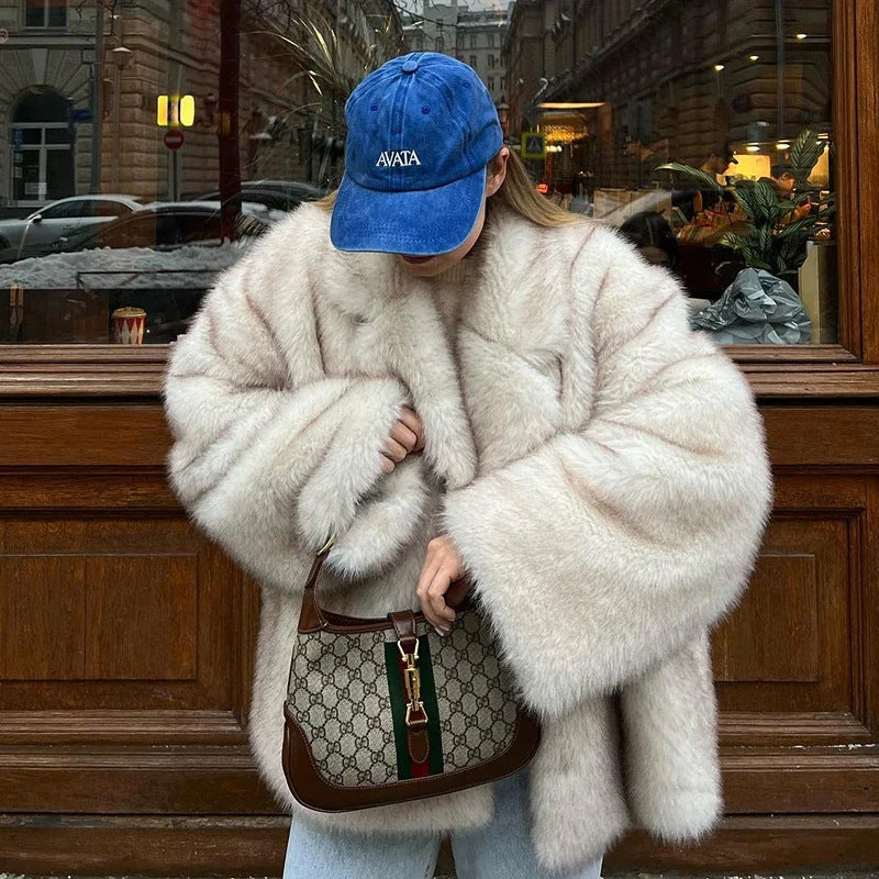 Person wearing a fluffy white coat and blue cap with a Gucci handbag in an urban setting.