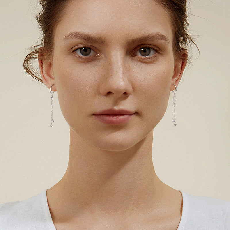 Close-up of a woman wearing silver earrings against a beige background