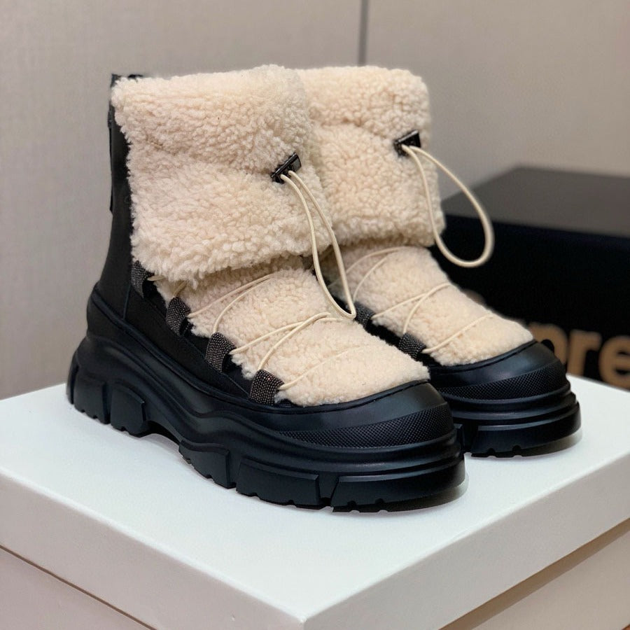 Black winter boots with beige fur lining on a white platform