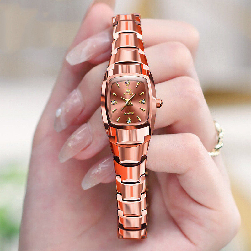 Rose gold watch held in a hand with a blurred background