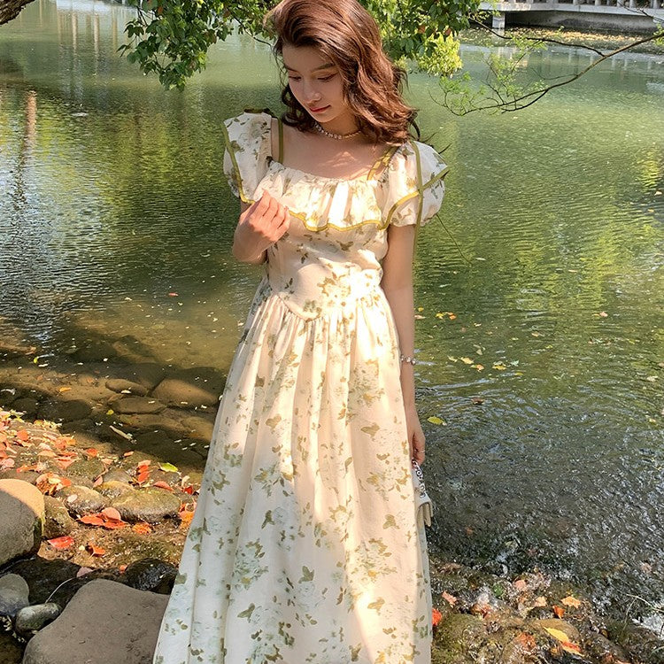 Woman in a floral dress standing by a pond with greenery