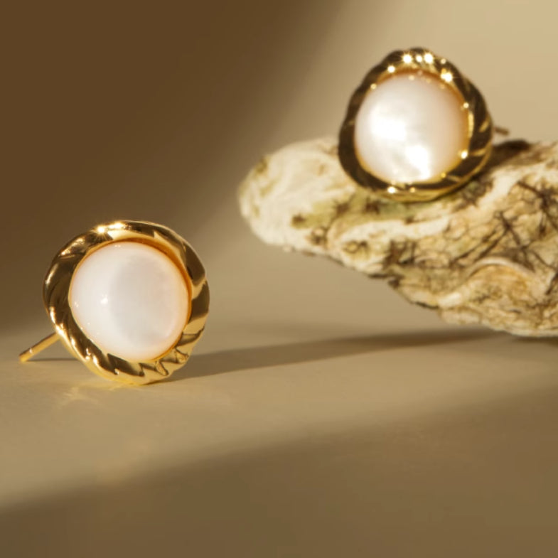 Gold earrings with white stones on a beige background