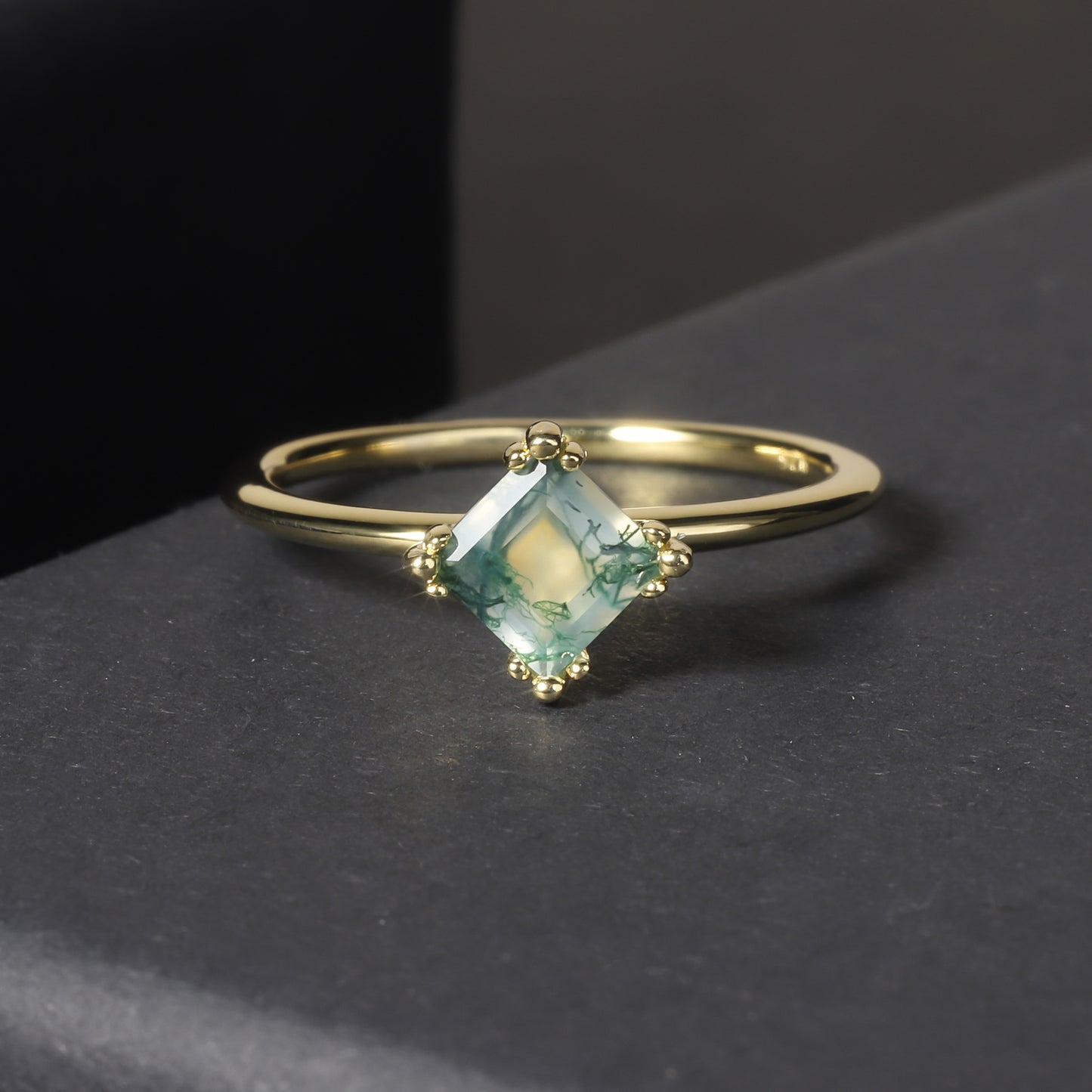 Gold ring with a green gemstone on a dark surface