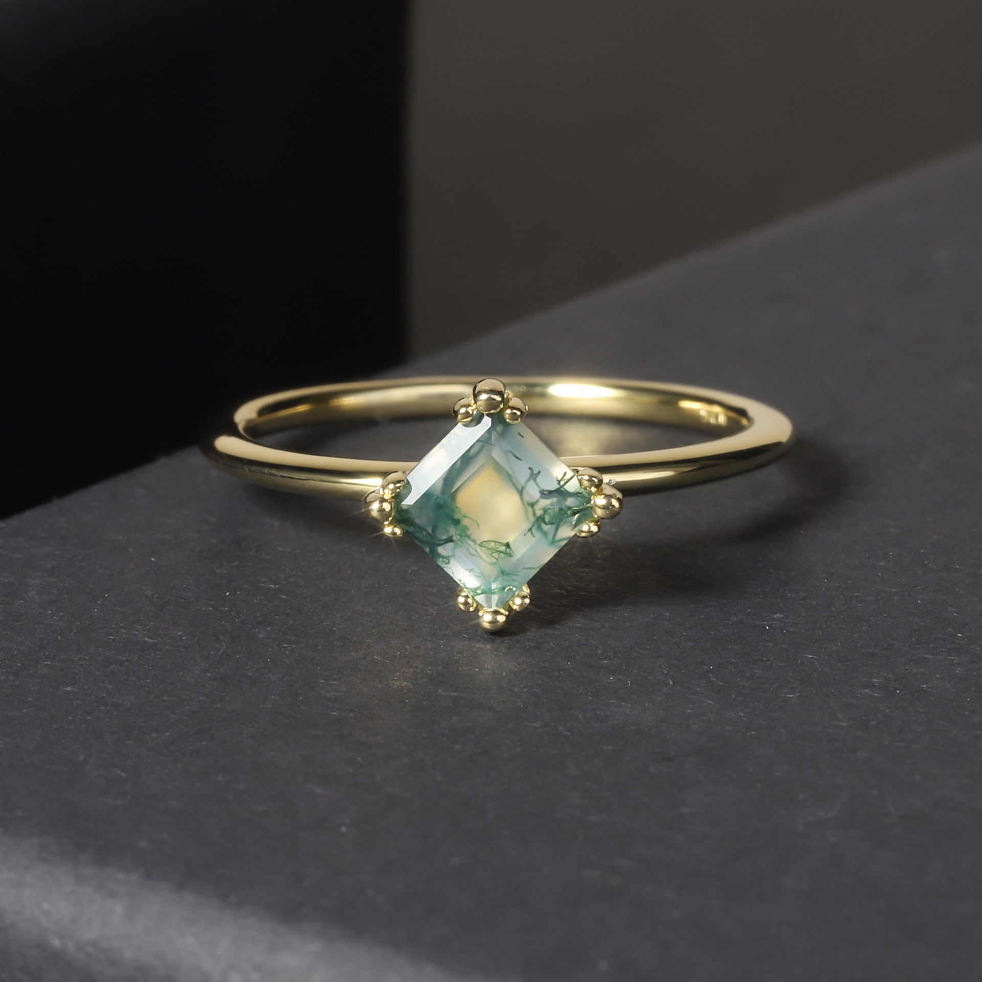 Gold ring with a green gemstone on a dark surface