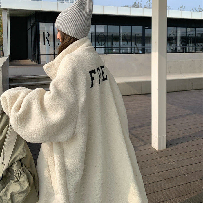 Person wearing a white fleece jacket with 'FRE' on the back, standing on a rooftop with cityscape in the background.