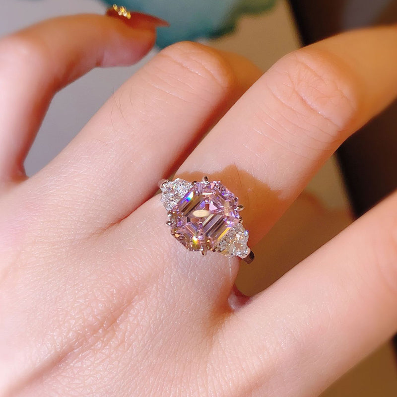 Close-up of a hand wearing a ring with a pink gemstone.