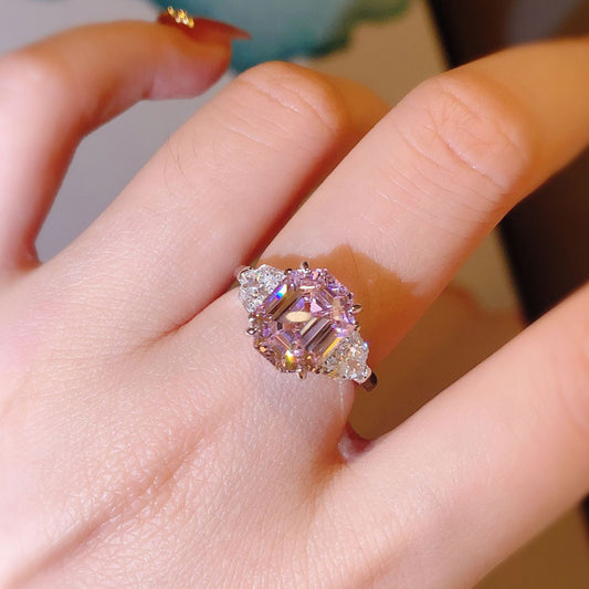 Close-up of a hand wearing a ring with a pink gemstone.