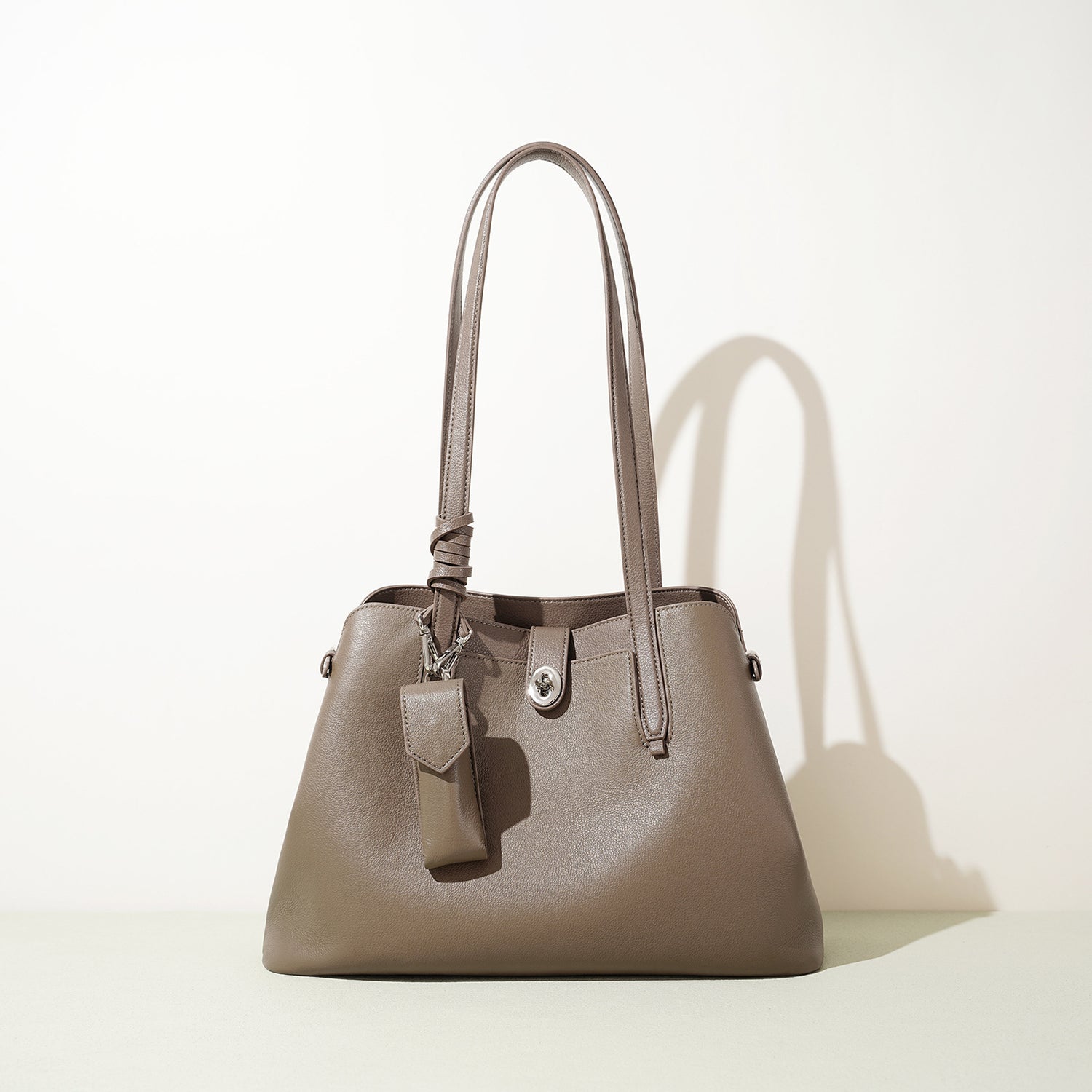 Beige handbag with a tag on a light beige background