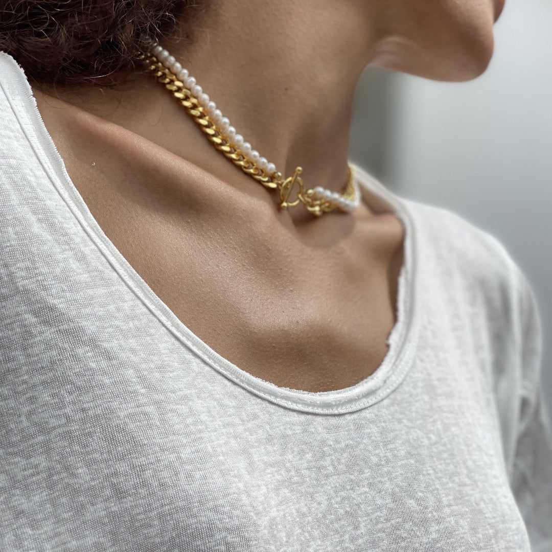 Close-up of a person wearing a gold necklace with a blurred background