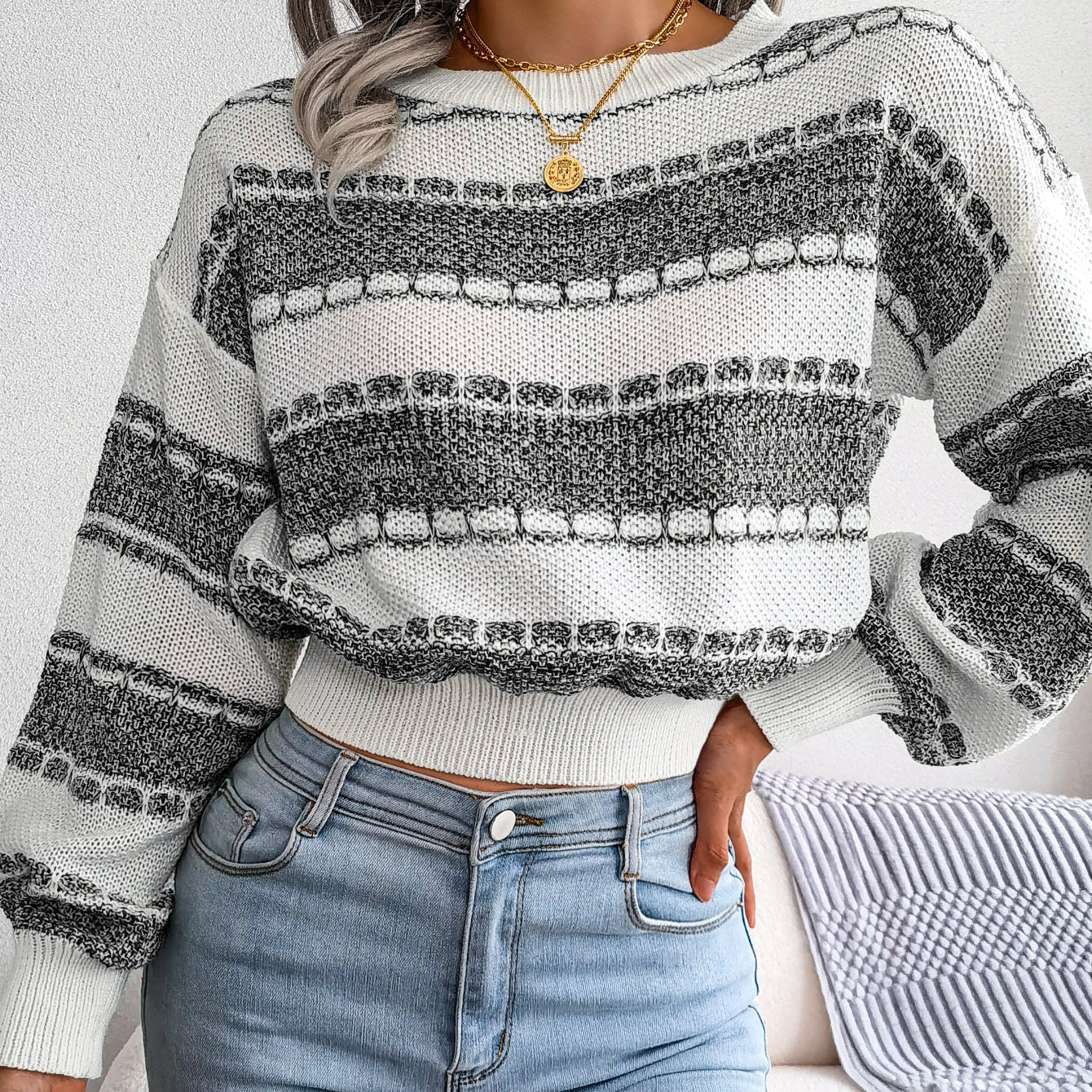 Person wearing a patterned sweater and jeans in a casual setting