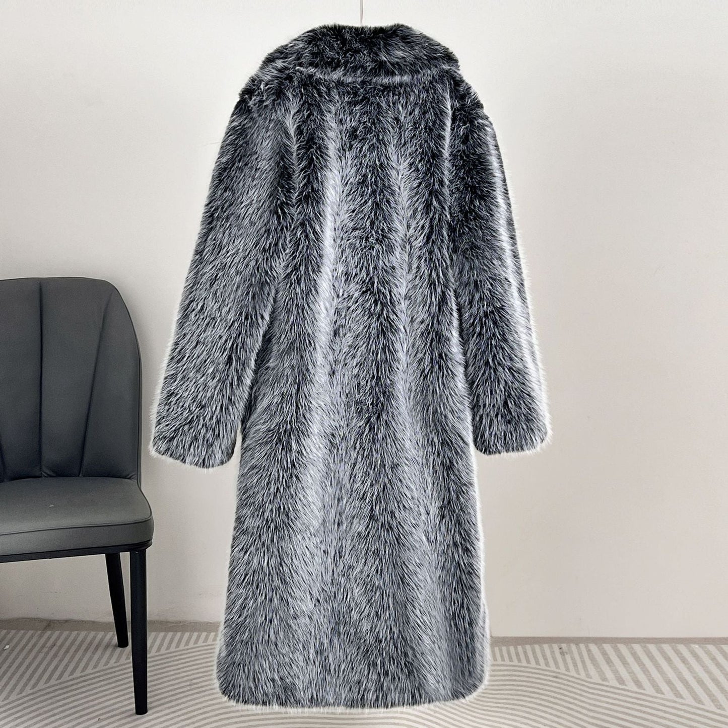 Gray fur coat hanging on a rack against a white wall.