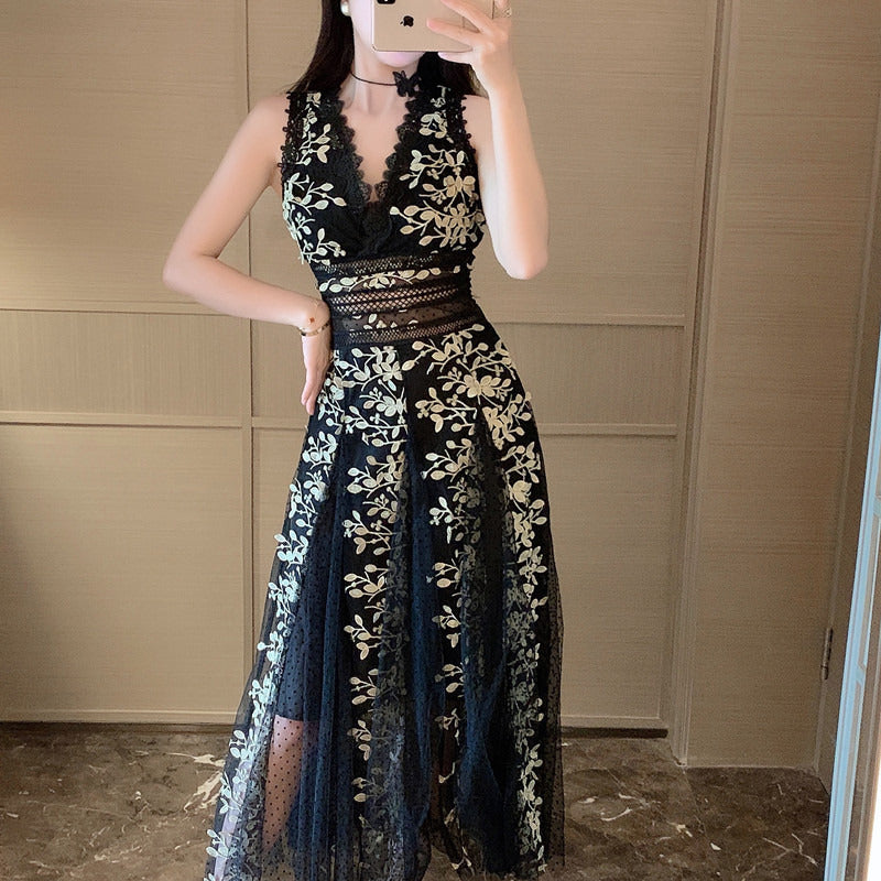 Person wearing a black and gold floral lace dress in front of a neutral wall.