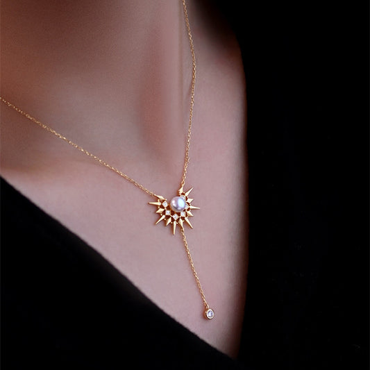 Gold necklace with a sun-shaped pendant on a person's neck against a dark background