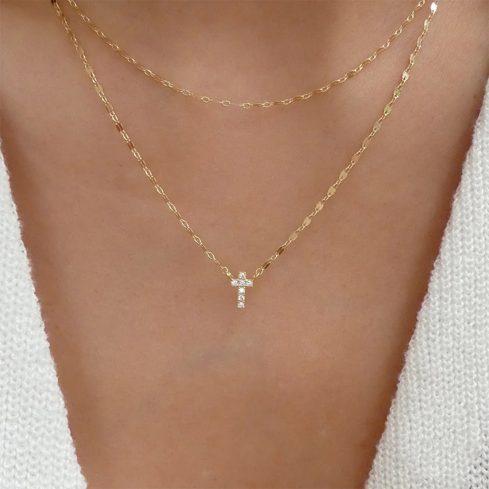 Gold necklace with a small cross pendant on a person's neck against a white background