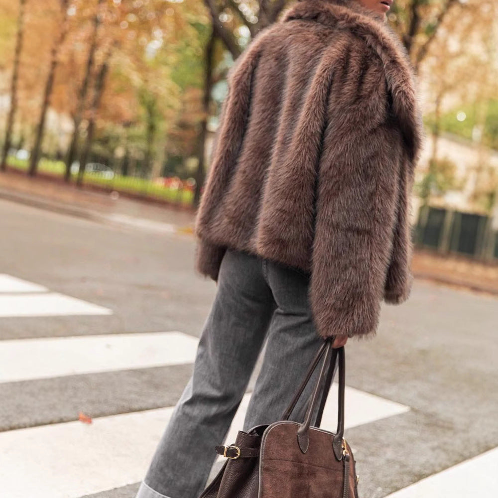 Person wearing a brown fur coat and holding a matching handbag on a city street.