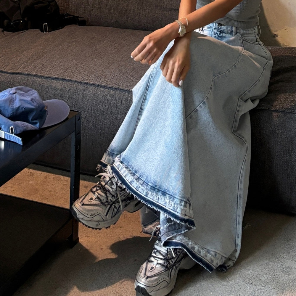 Person wearing light blue jeans and sneakers sitting on a couch.