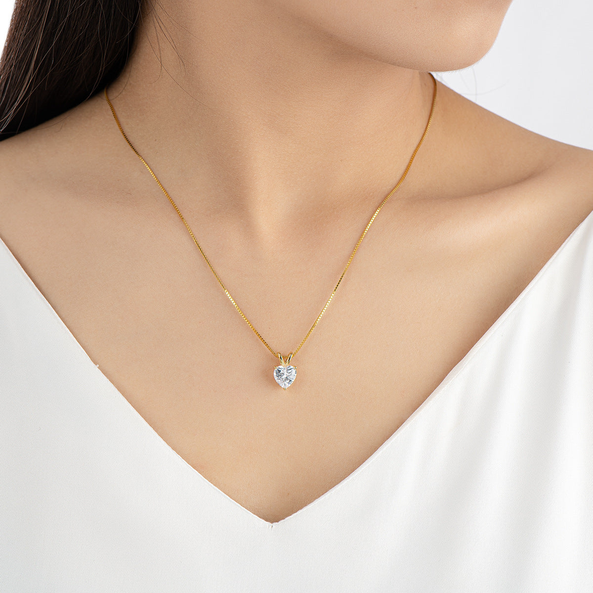 Gold necklace with a heart-shaped pendant on a white background