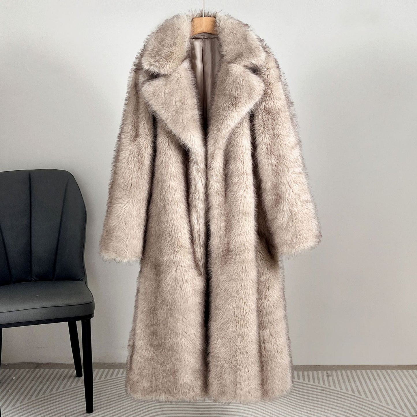 Beige fur coat on a hanger against a plain wall with a black chair in the corner.