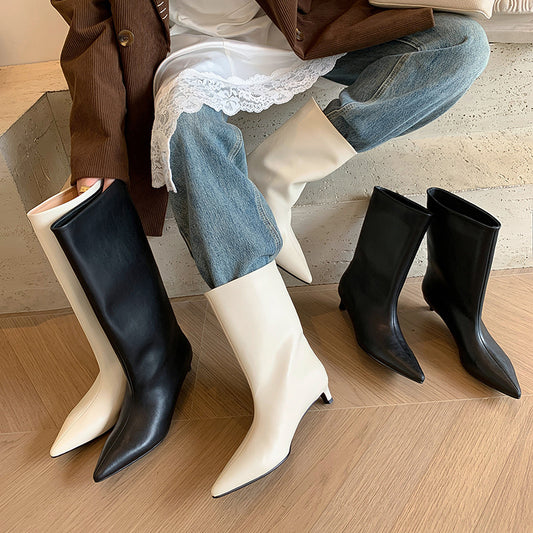 White and black knee-high boots displayed on a mannequin with a neutral background