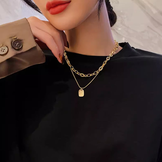 Person wearing a gold chain necklace with a pendant, close-up on the neck and collarbone.