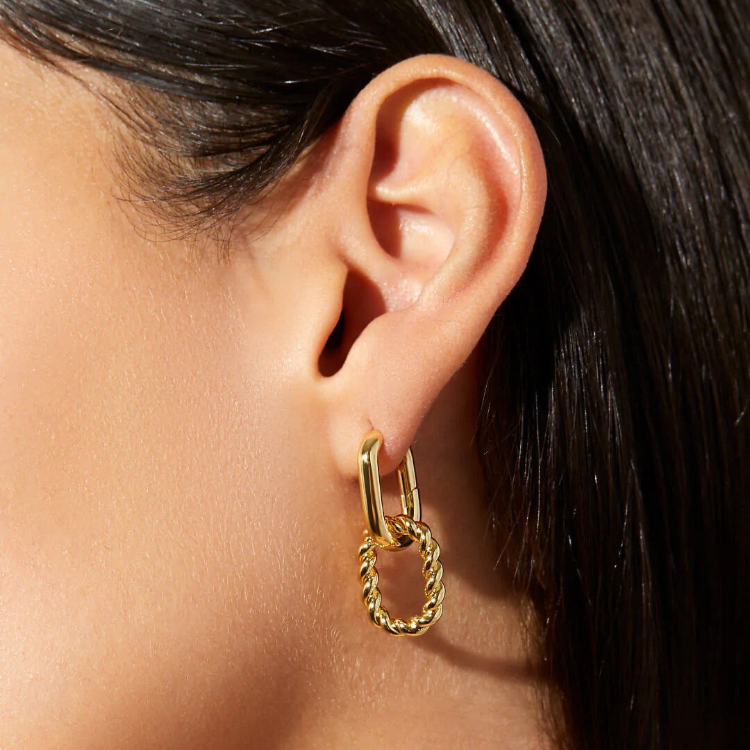 Gold hoop earring worn by a person with dark hair.