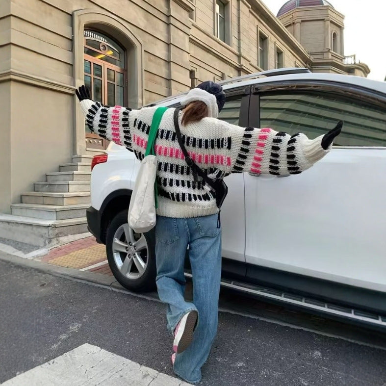 Person wearing a colorful sweater and jeans standing next to a white car on a city street.