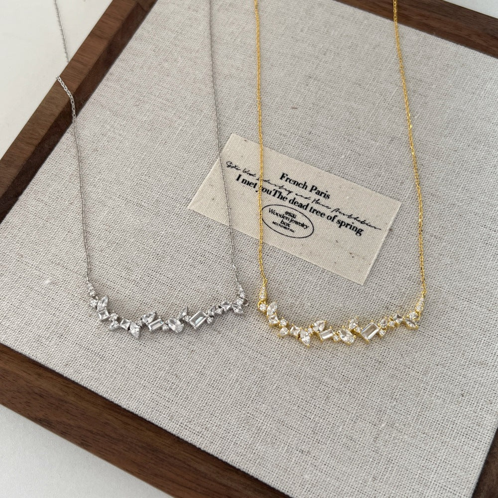 Two necklaces on a textured surface with a card in the background