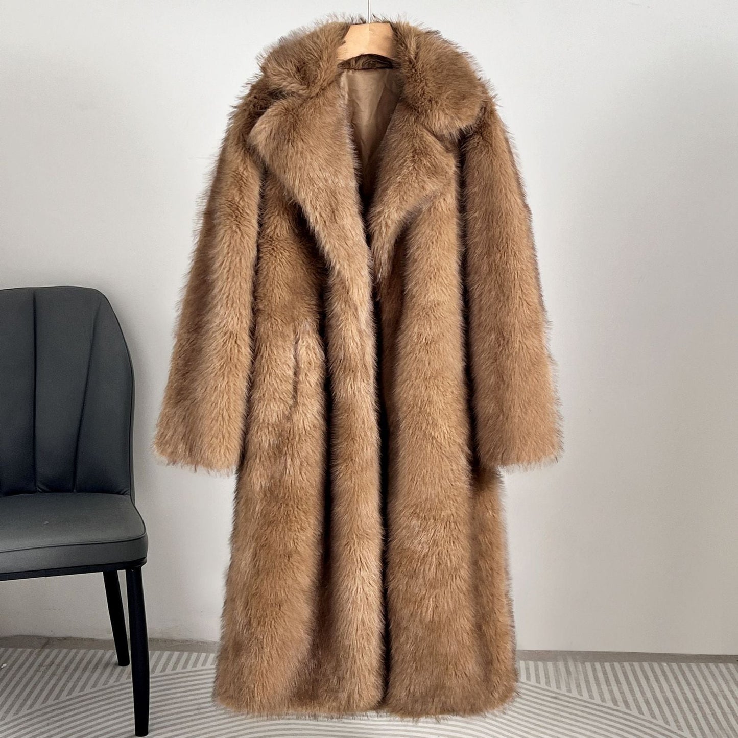 Brown fur coat on a hanger against a white wall with a black chair.