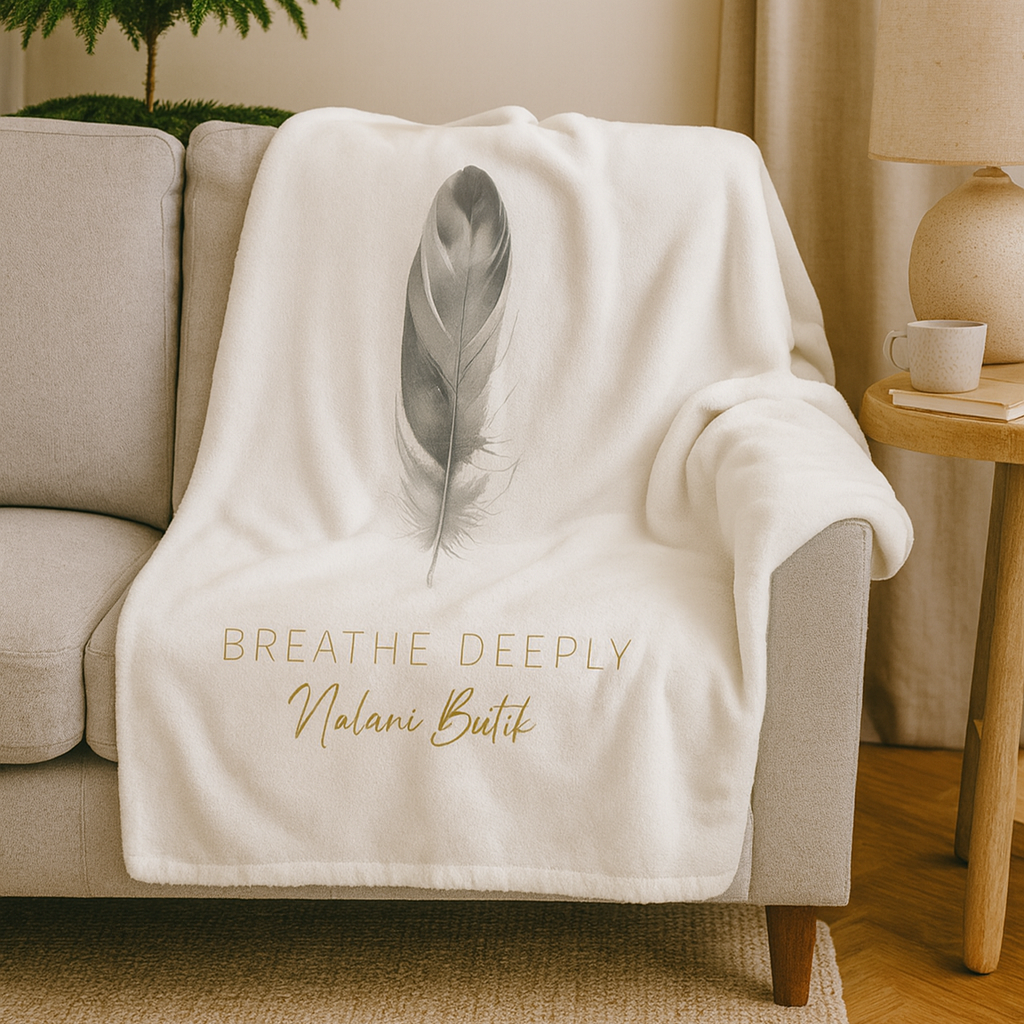 White blanket with feather design and text draped over a couch in a living room.