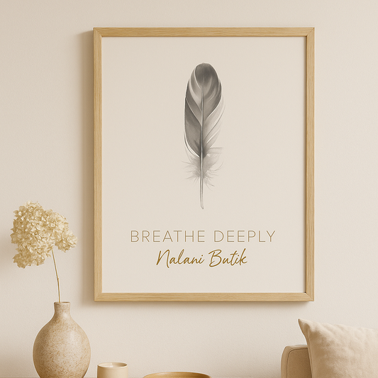 Framed artwork with a feather and text on a wall above a wooden table with decorative items.