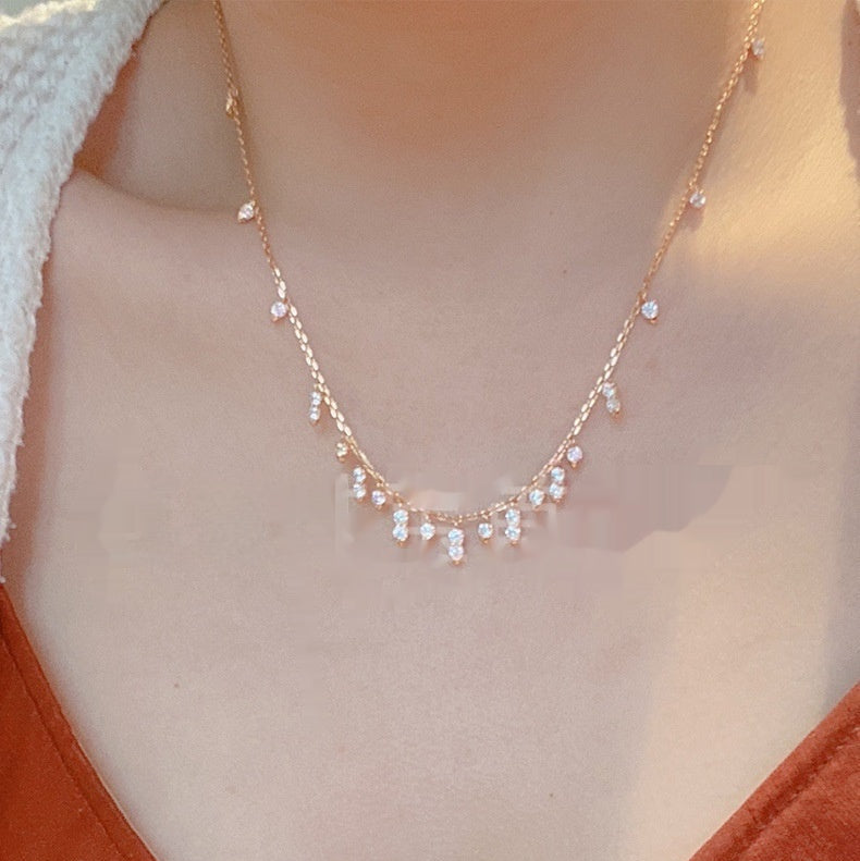 Necklace with small beads and crystals worn by a person in an orange top.