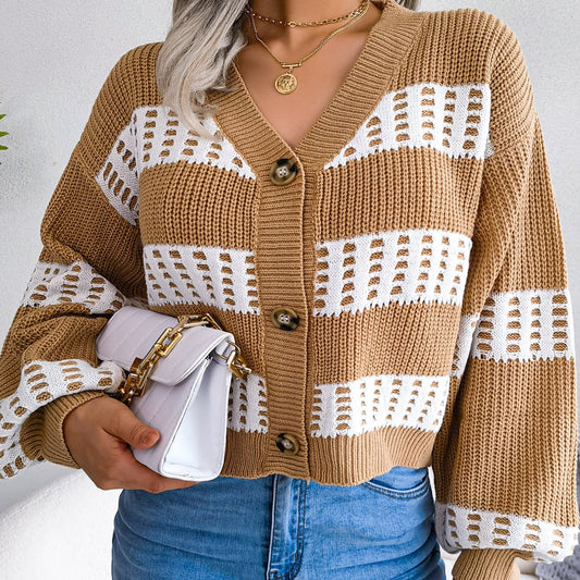 Person wearing a brown and white patterned cardigan with blue jeans against a plain background