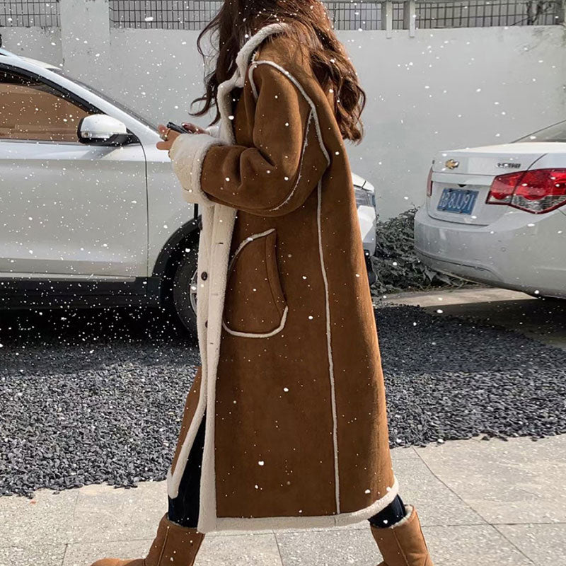 Person wearing a brown coat with white trim walking on a snowy street.