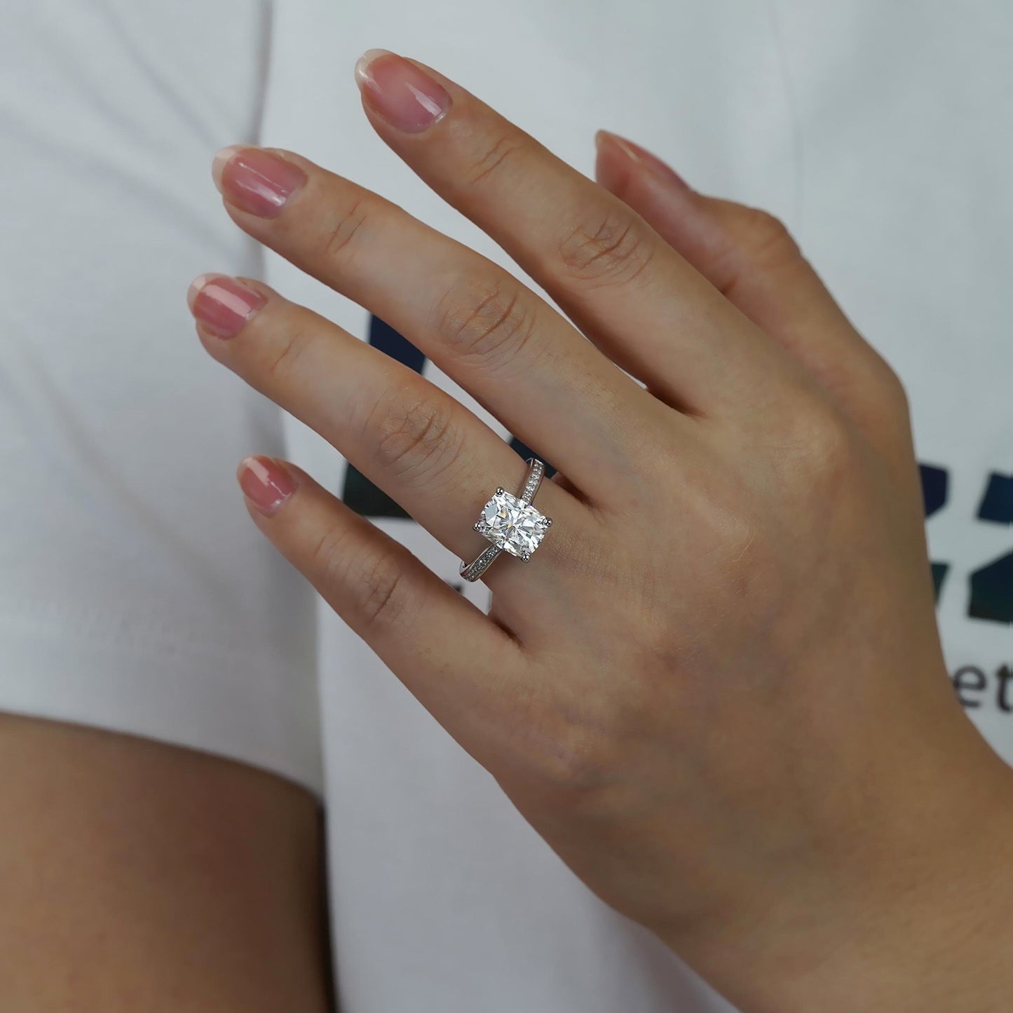Hand wearing a diamond ring with a blurred background