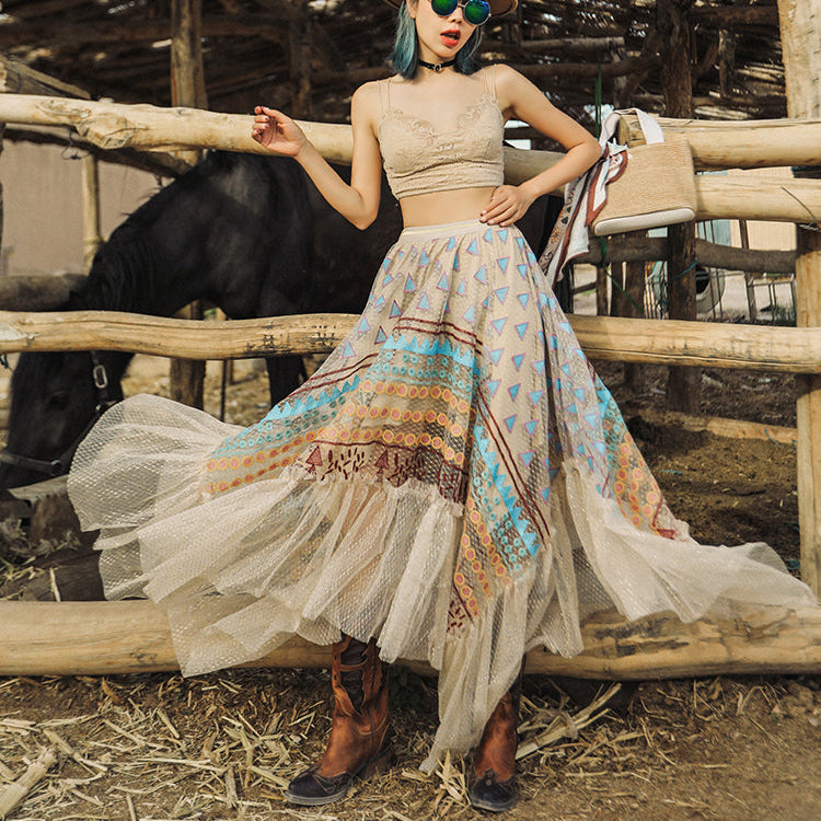 Woman in a patterned dress and hat standing in a rustic setting with a horse.