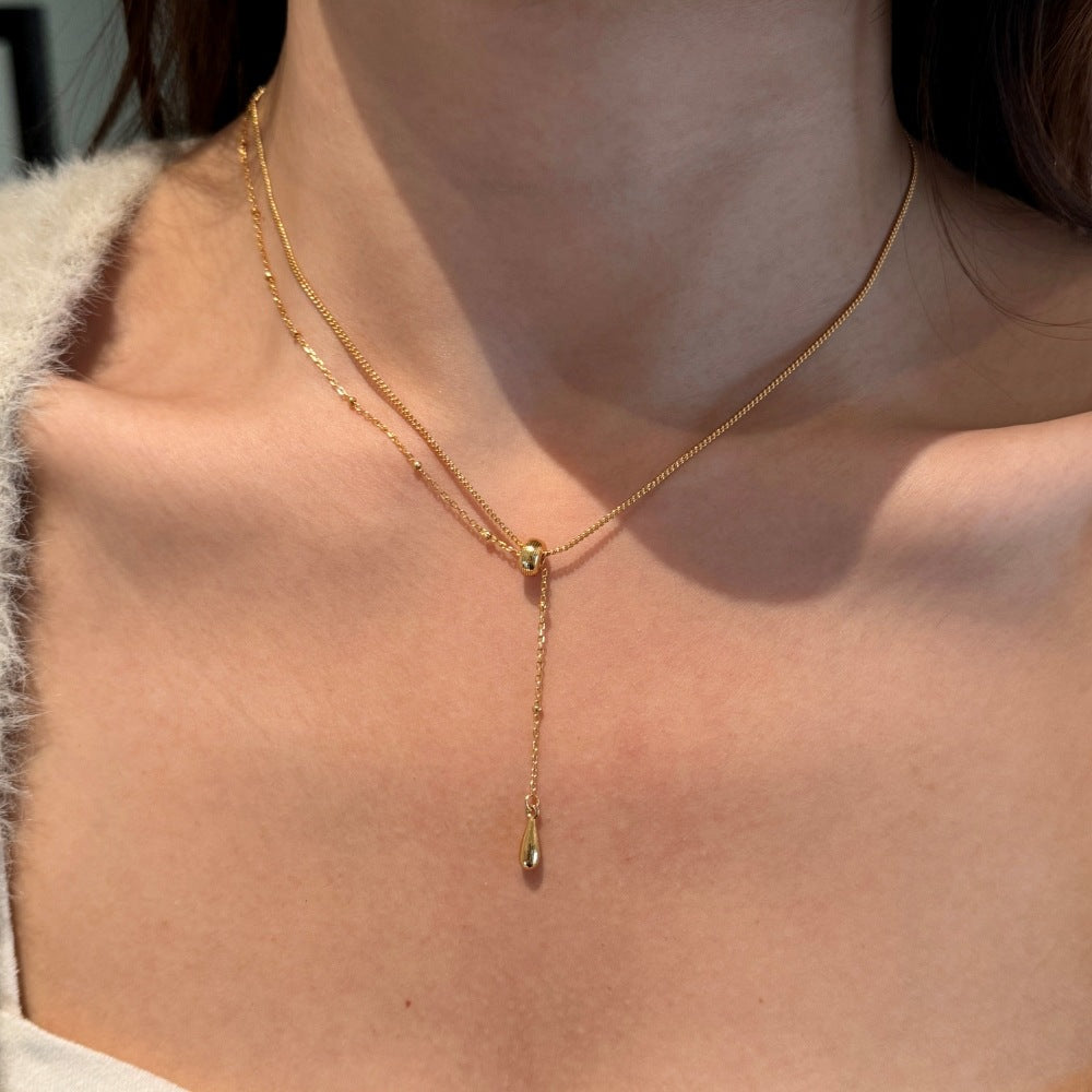Gold necklace with a teardrop pendant on a person's neck