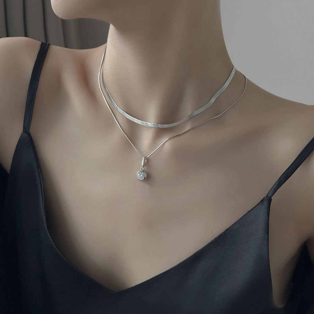 Silver necklace with a pendant on a mannequin wearing a black top.