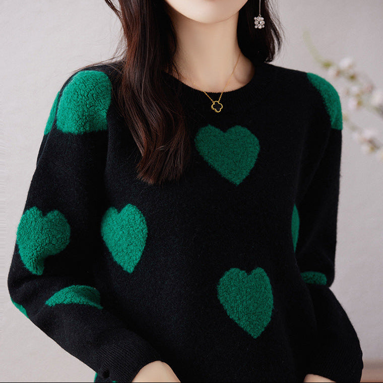 Person wearing a black sweater with green hearts against a neutral background