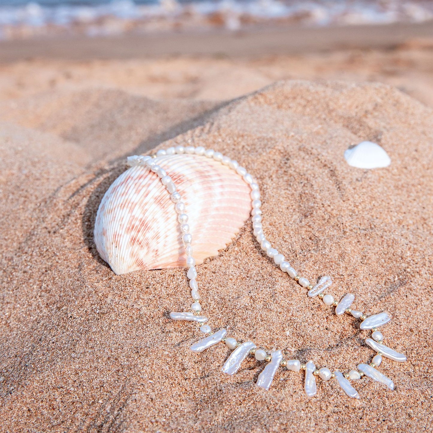 Pearl necklace with a shell on sand by the sea
