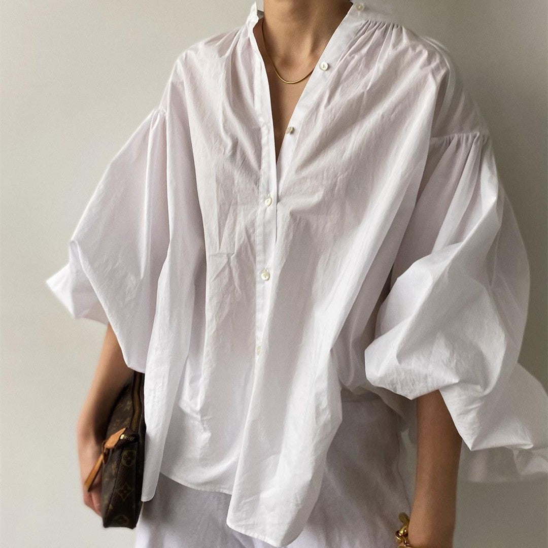 Person wearing an oversized white shirt with a neutral background