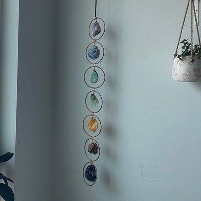 Decorative hanging with stones on a wall next to a window