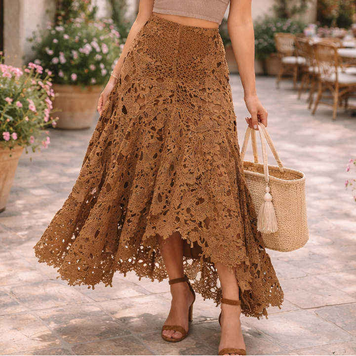 Woman in a brown lace skirt and beige top standing in an outdoor setting with flowers and tables.