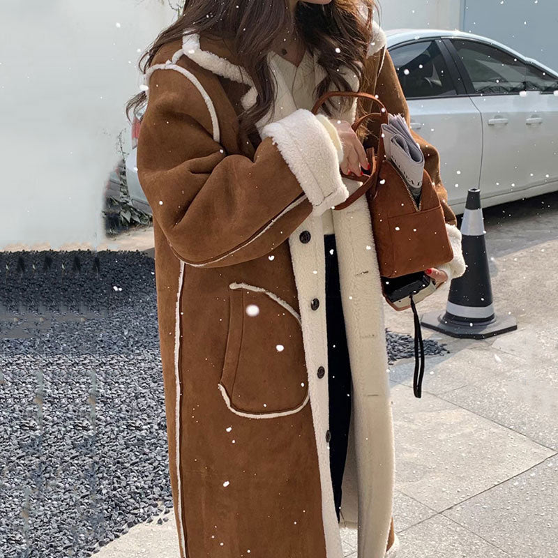 Person wearing a long brown coat with white trim in a snowy outdoor setting.