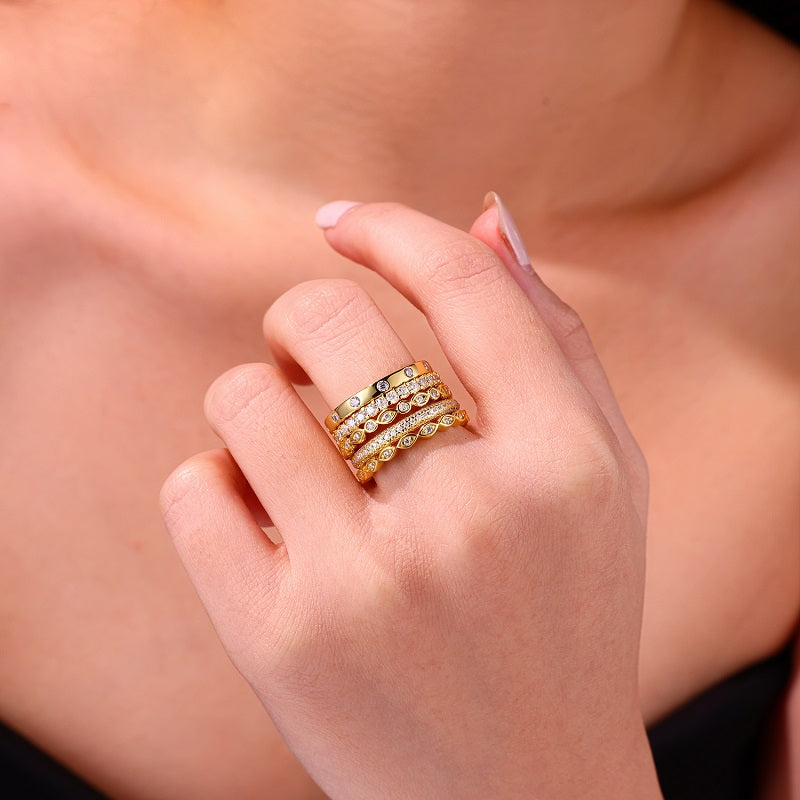 Hand wearing multiple gold rings with a blurred background