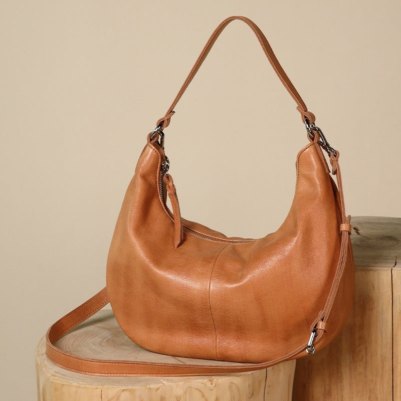 Brown leather handbag on a wooden surface with a beige background