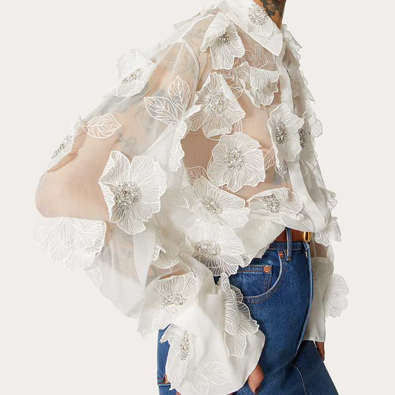 White floral lace top over blue jeans on a white background